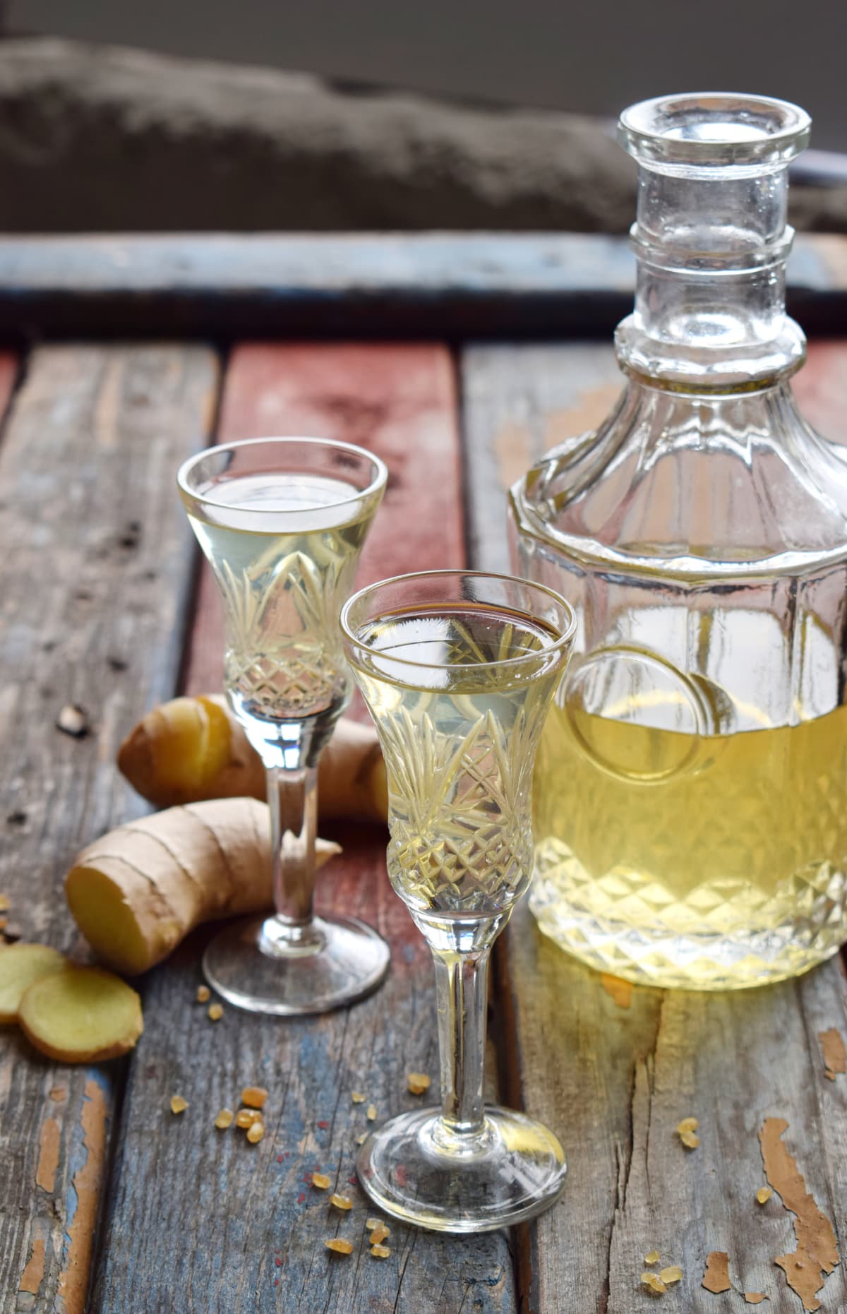 Ginger tincture or ale on wooden background. Spice yellow liqueur in a glass. Homemade Alcohol drink. Rustic style