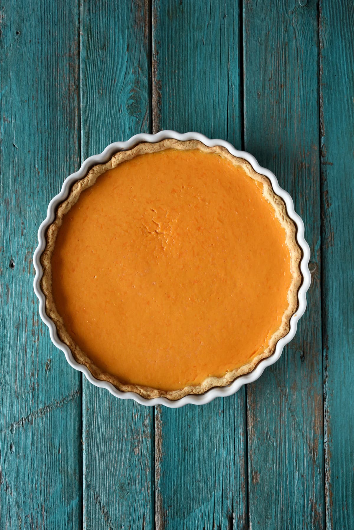 Pumpkin pie in a baking dish on blue wooden surface