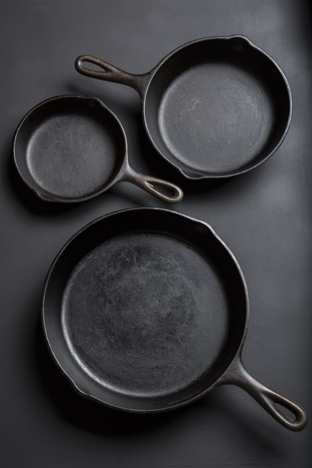 3 cast iron skillets on a counter. 