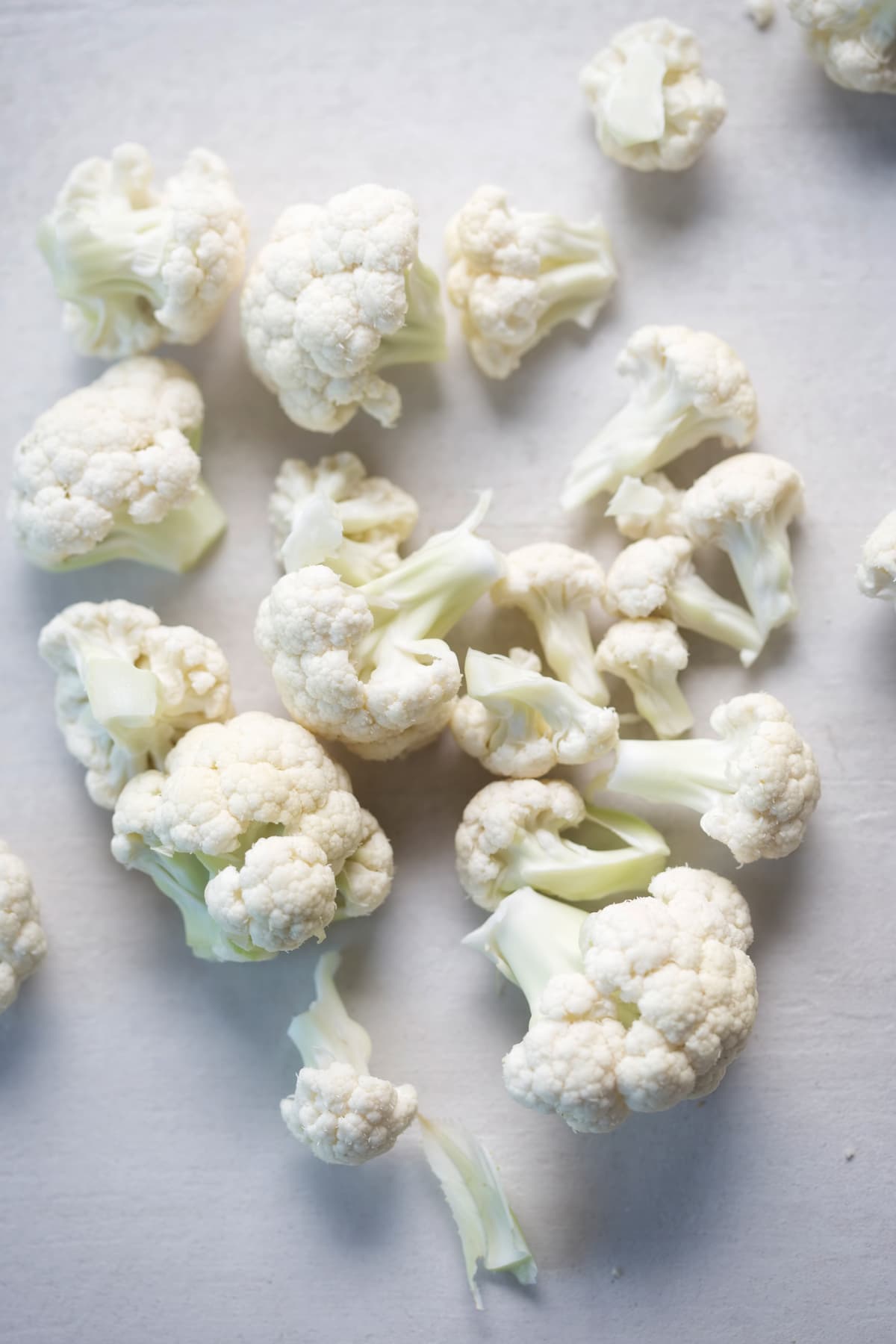 Cauliflower cut into florets on white surface