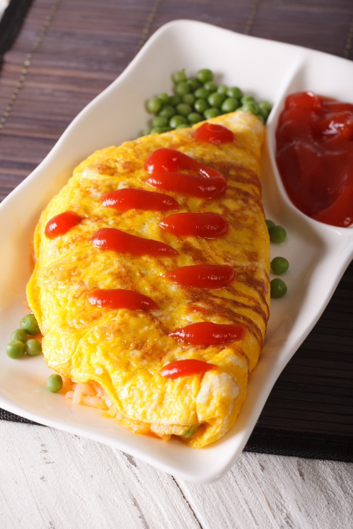 Japanese omelet stuffed with rice and chicken close-up on a plate. vertical
