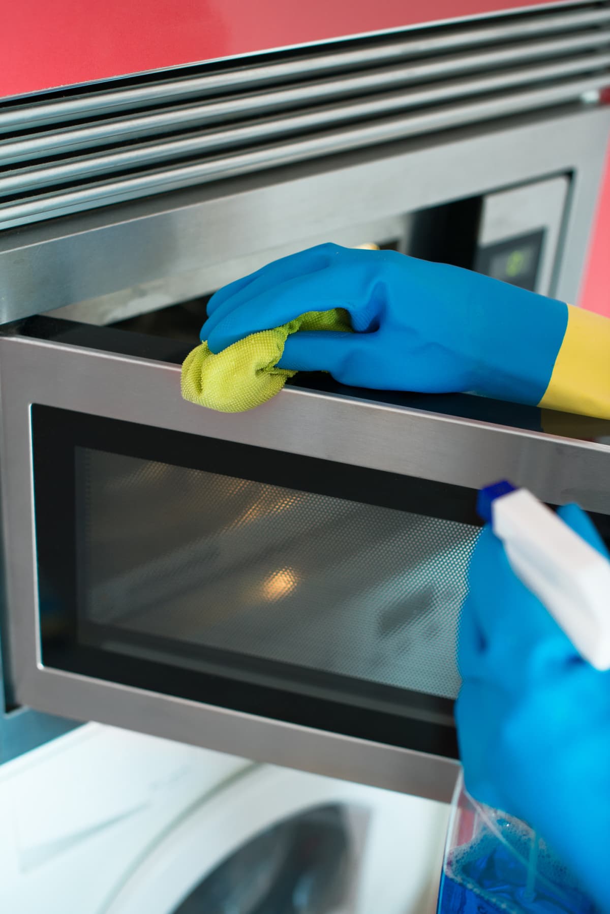 Person in gloves cleaning microwave oven, closeup