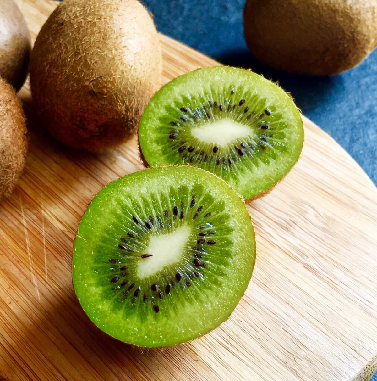Kiwi slices in the bowl. On black wooden background