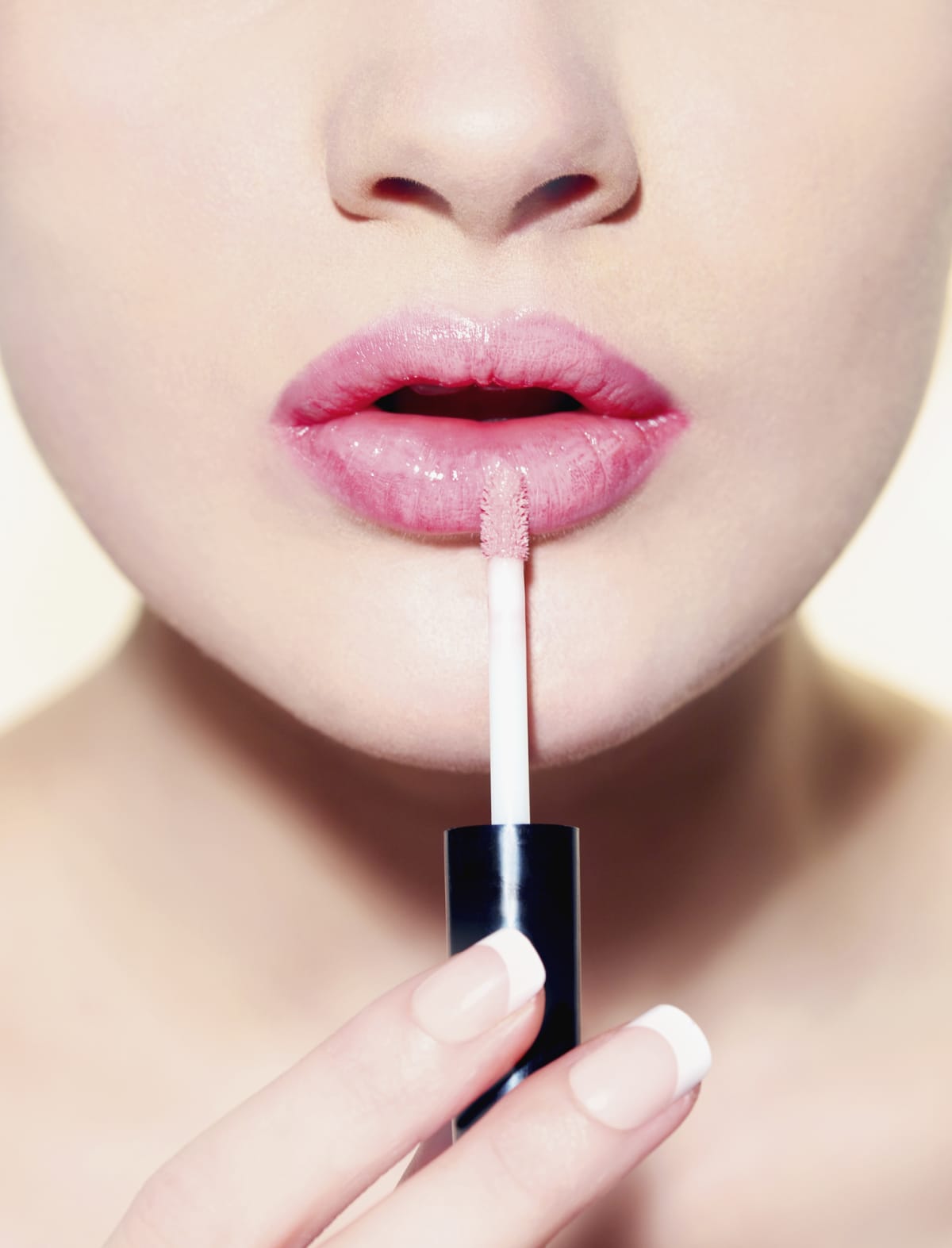 Closeup of a woman applying pink lip gloss to her lips