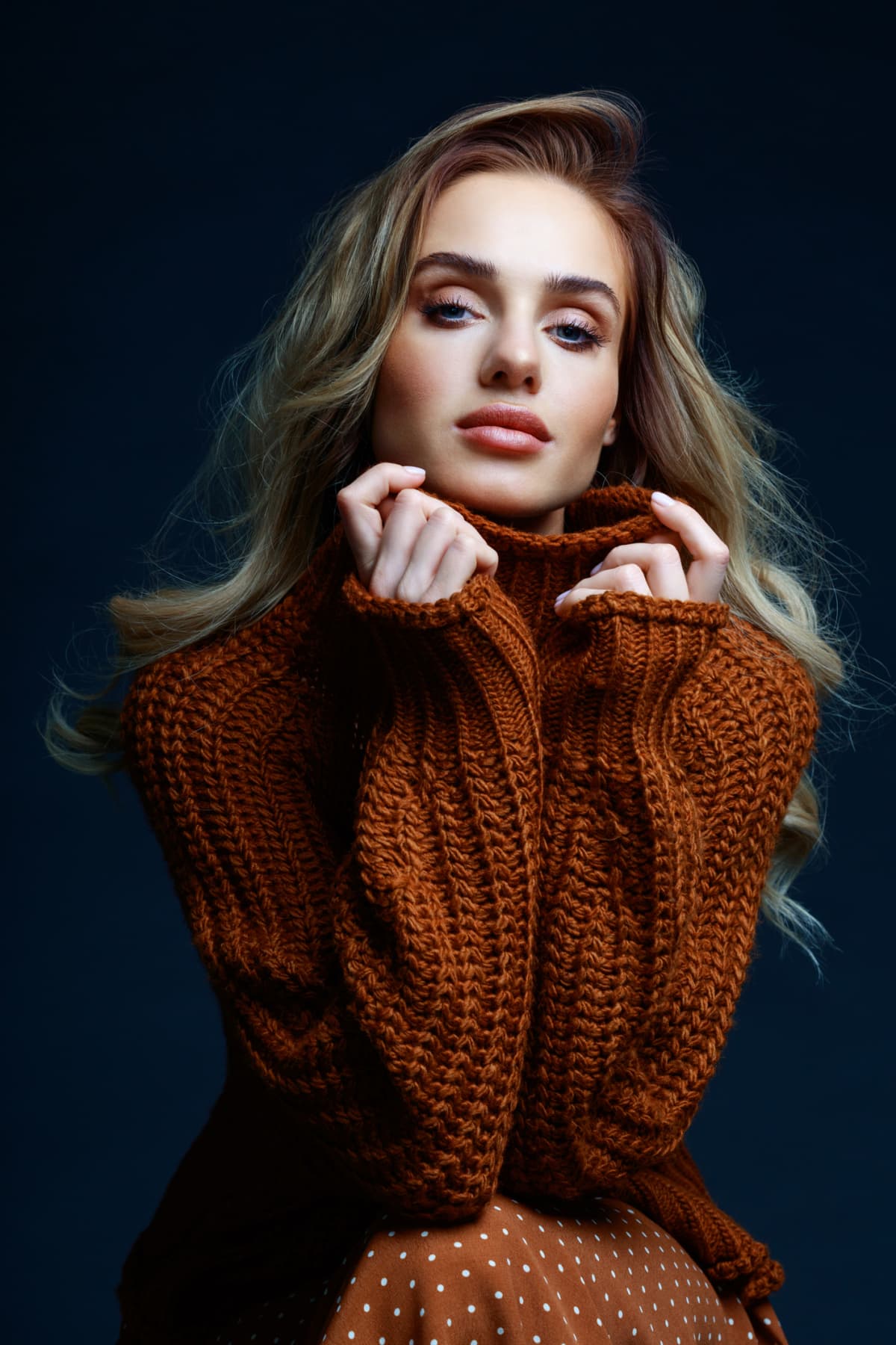 Beautiful woman with natural makeup, false eyelashes strikes a confident pose while wearing an oversized sweater 