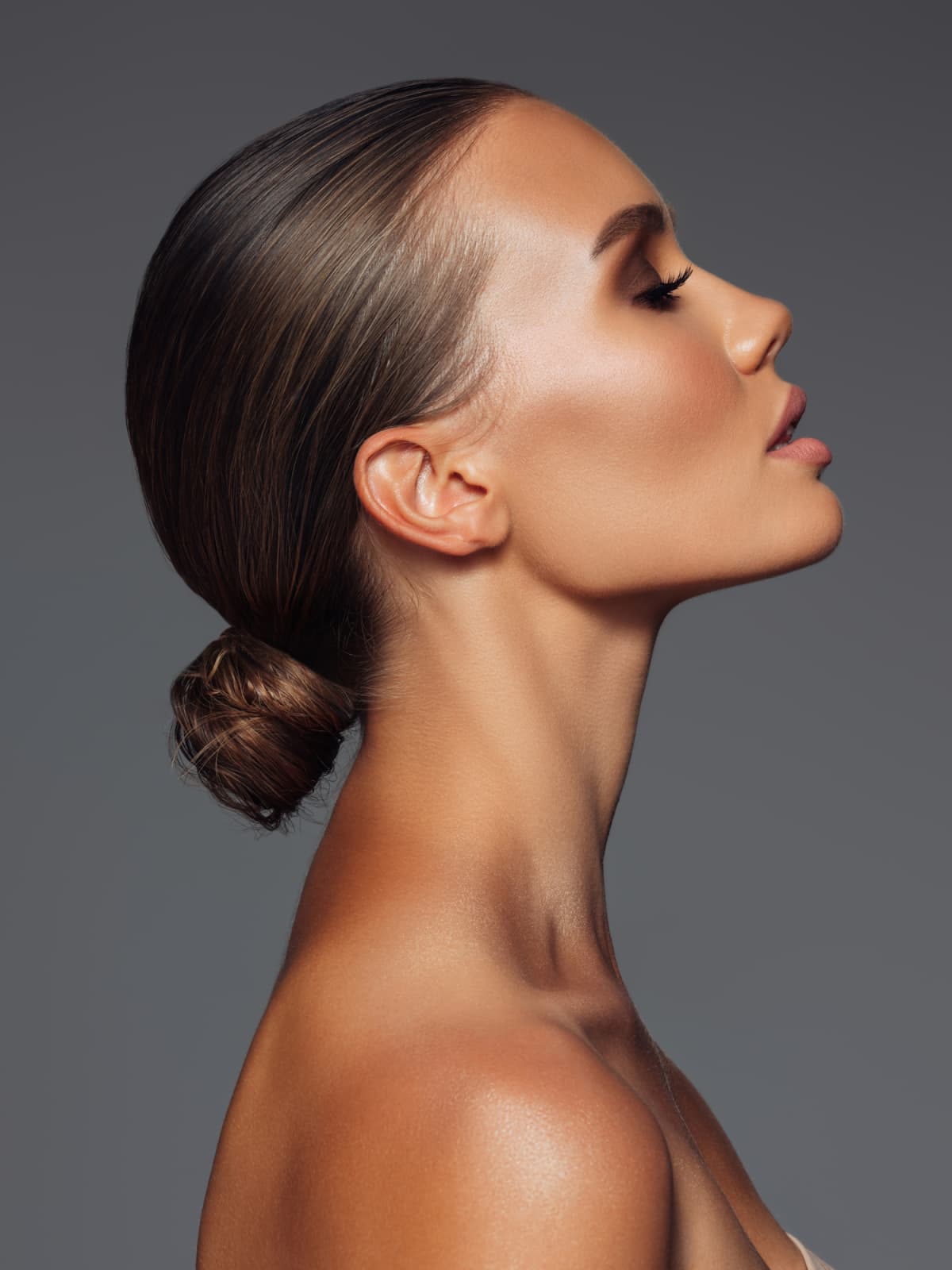 A woman with glowing skin and shiny hair in profile