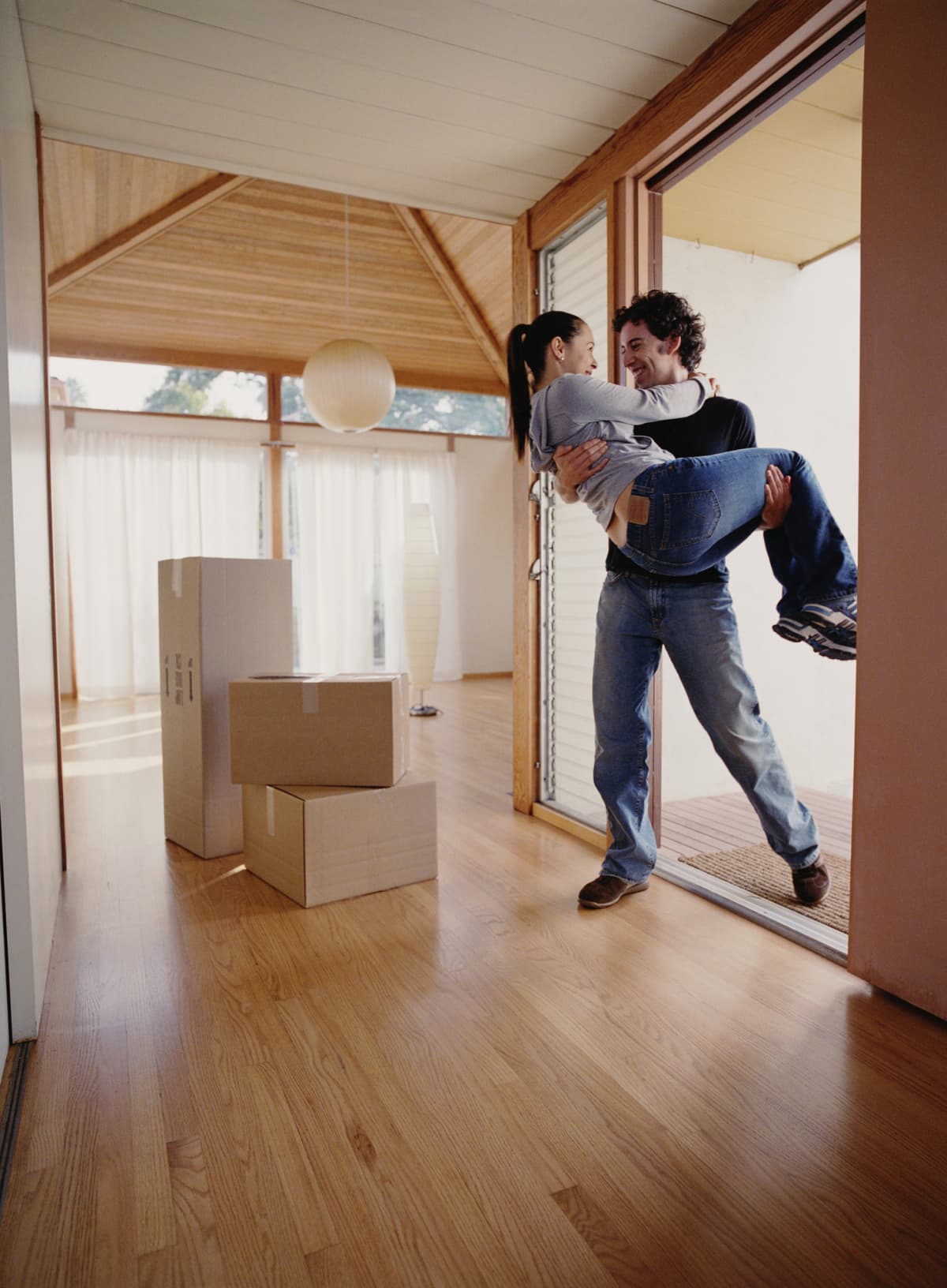 A man carries his girlfriend over the threshold as they move in together
