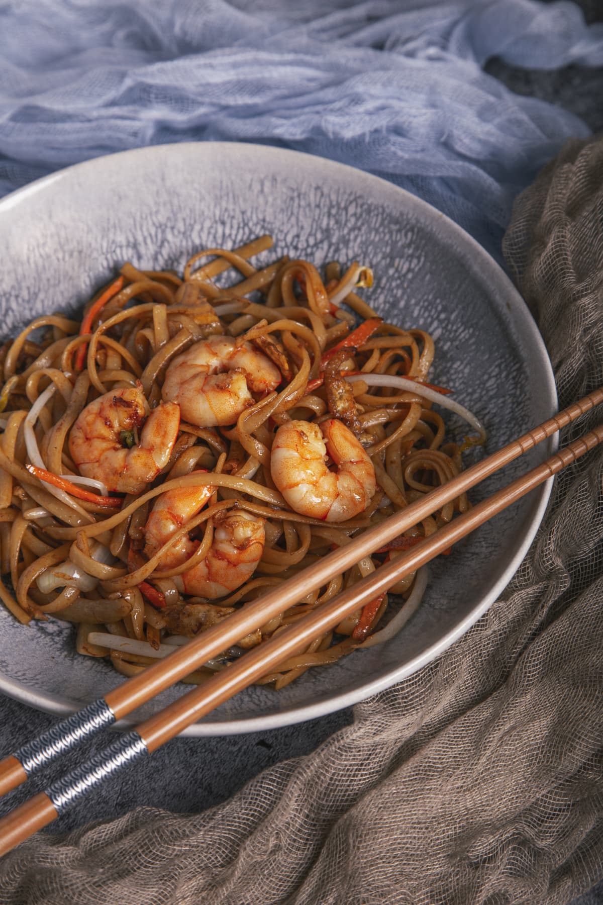 Close up of a bowl of Chinese noodles with shrimp and chopsticks. Chinese cuisine.
