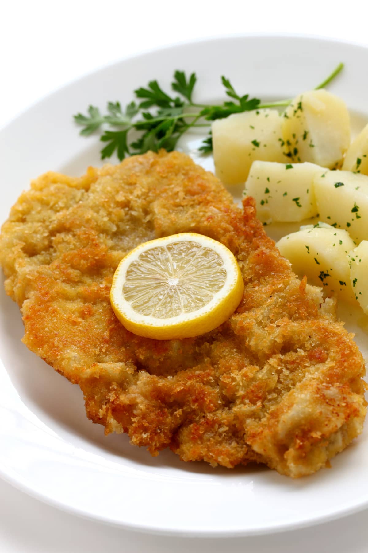 Breaded cut of meat on a plate with potatoes