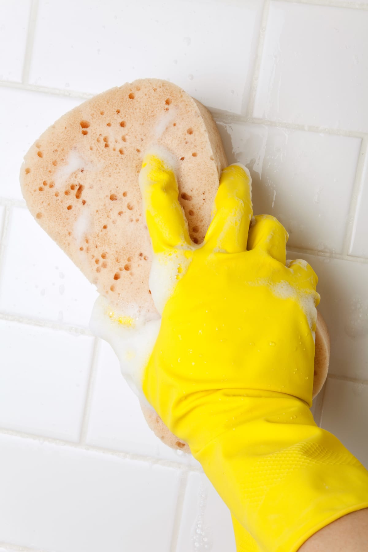 A person cleaning grout with a sponge