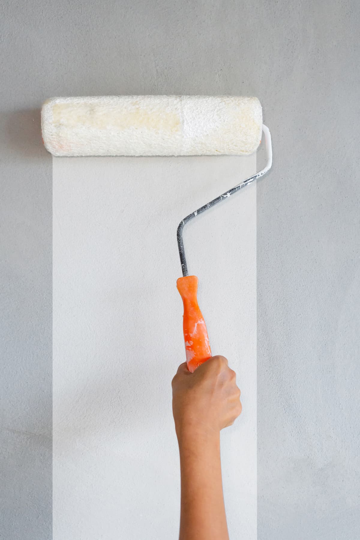 White paint being rolled onto a concrete wall