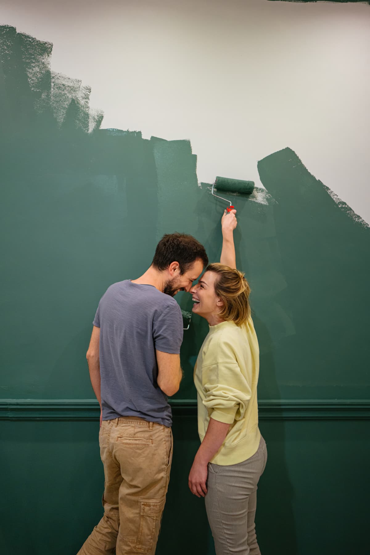 Young couple painting the walls of their new apartment green