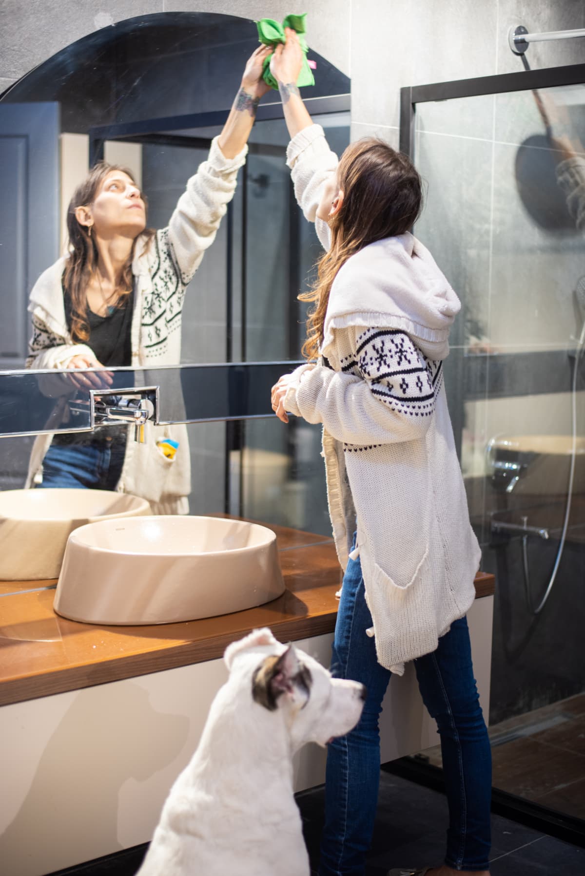 A woman cleaning a bathroom mirror