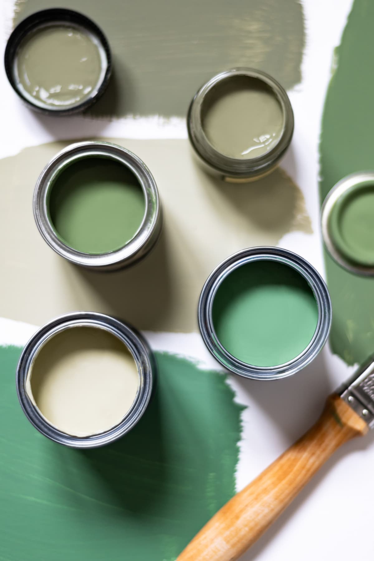 Tiny sample paint cans during house renovation, process of choosing paint for the walls, different green colors, color samples on background.