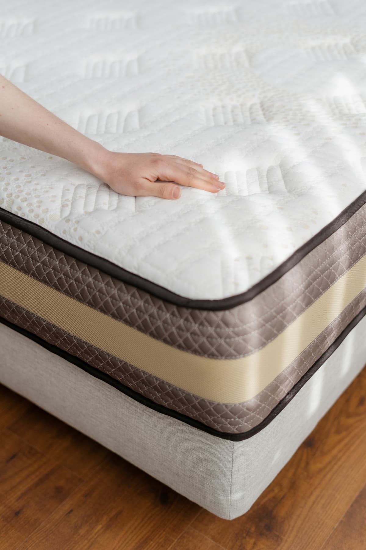 A person with their hand on a mattress