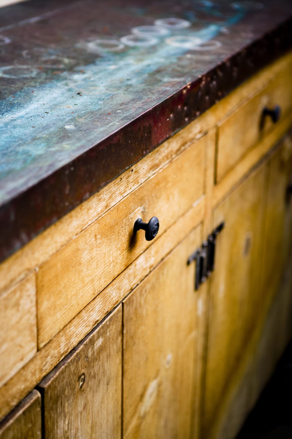 Vintage wooden kitchen cabinets with a worn, dark countertop