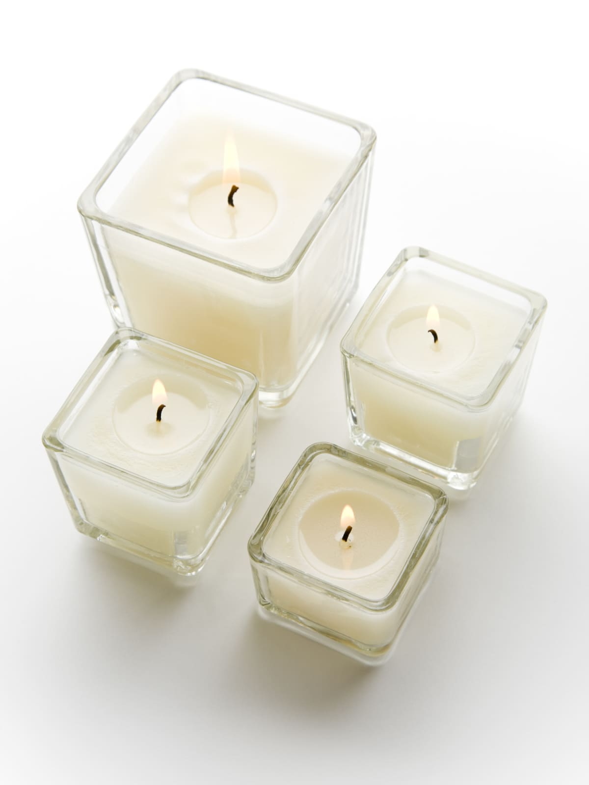 Three lit white candles in glass containers