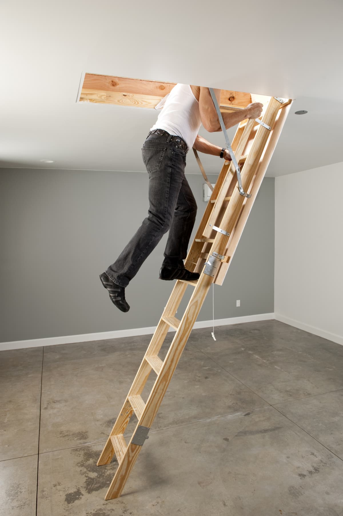 Person climbing the pull-down stairs to the garage attic storage area