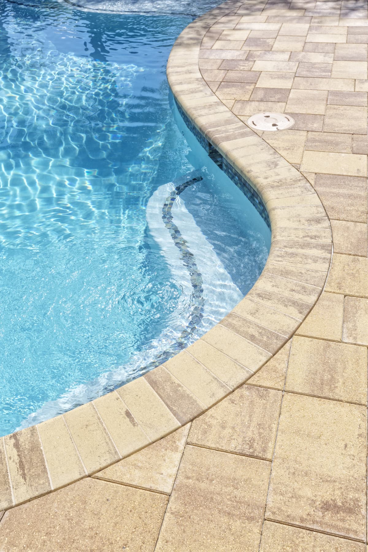 Close up of a new swimming pool with bench and pavers.
