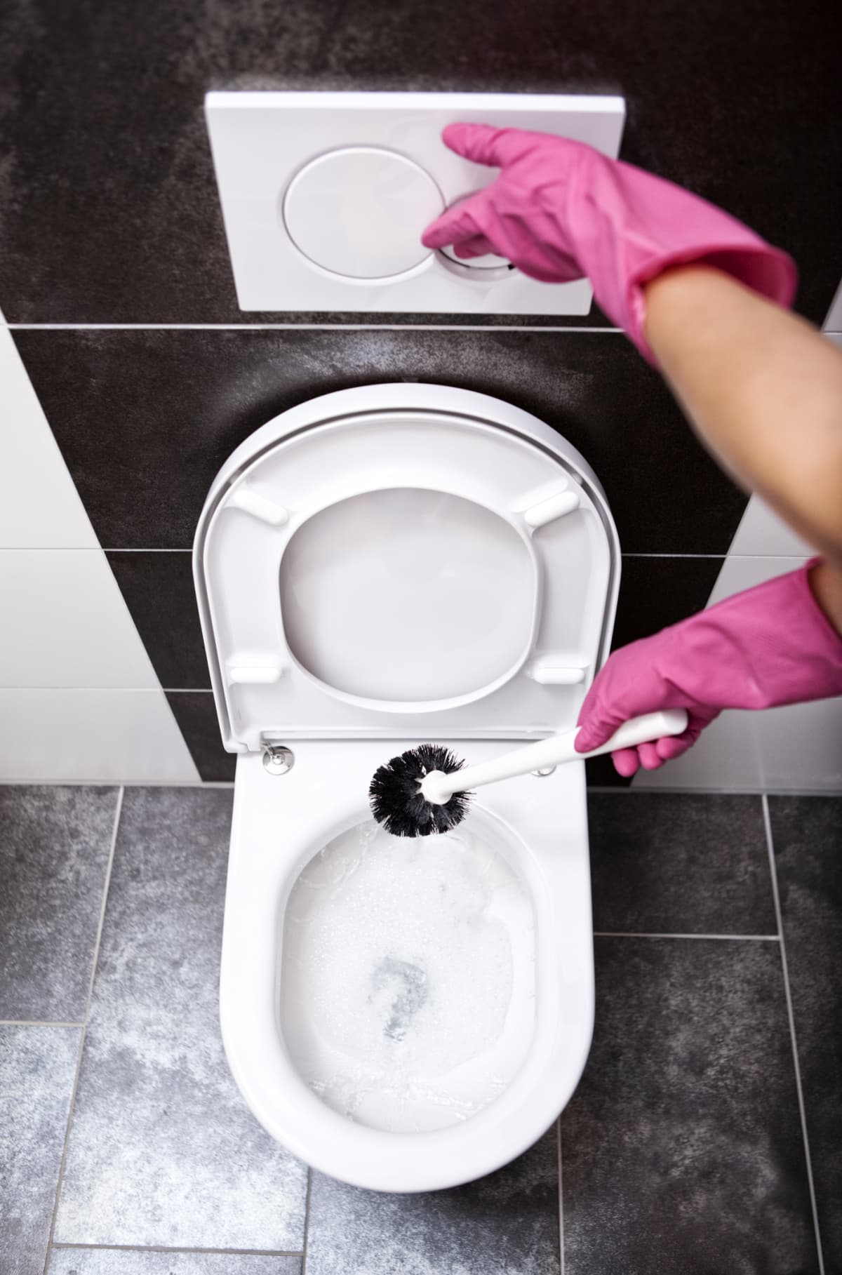 A person cleaning the toilet with toilet brush