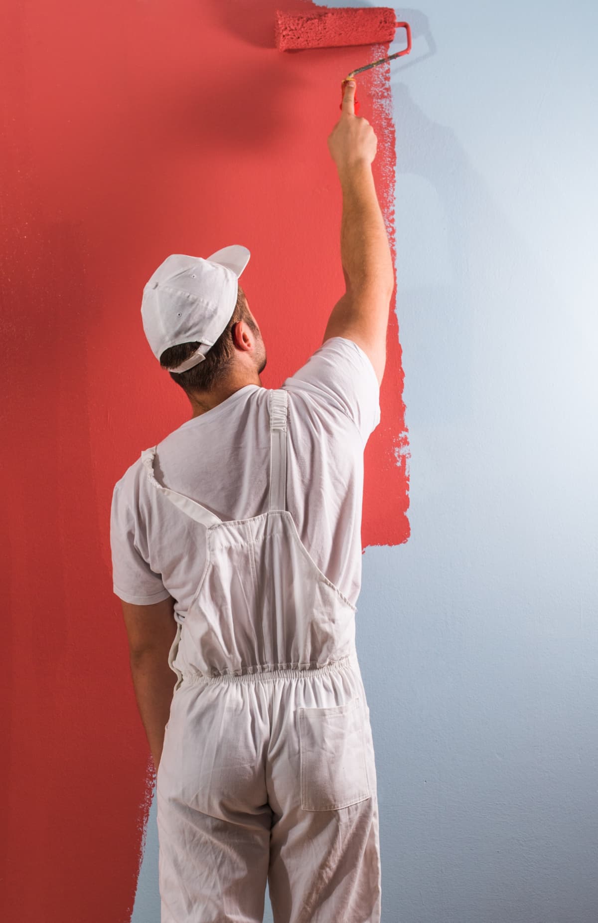 A painter using roller to paint wall red