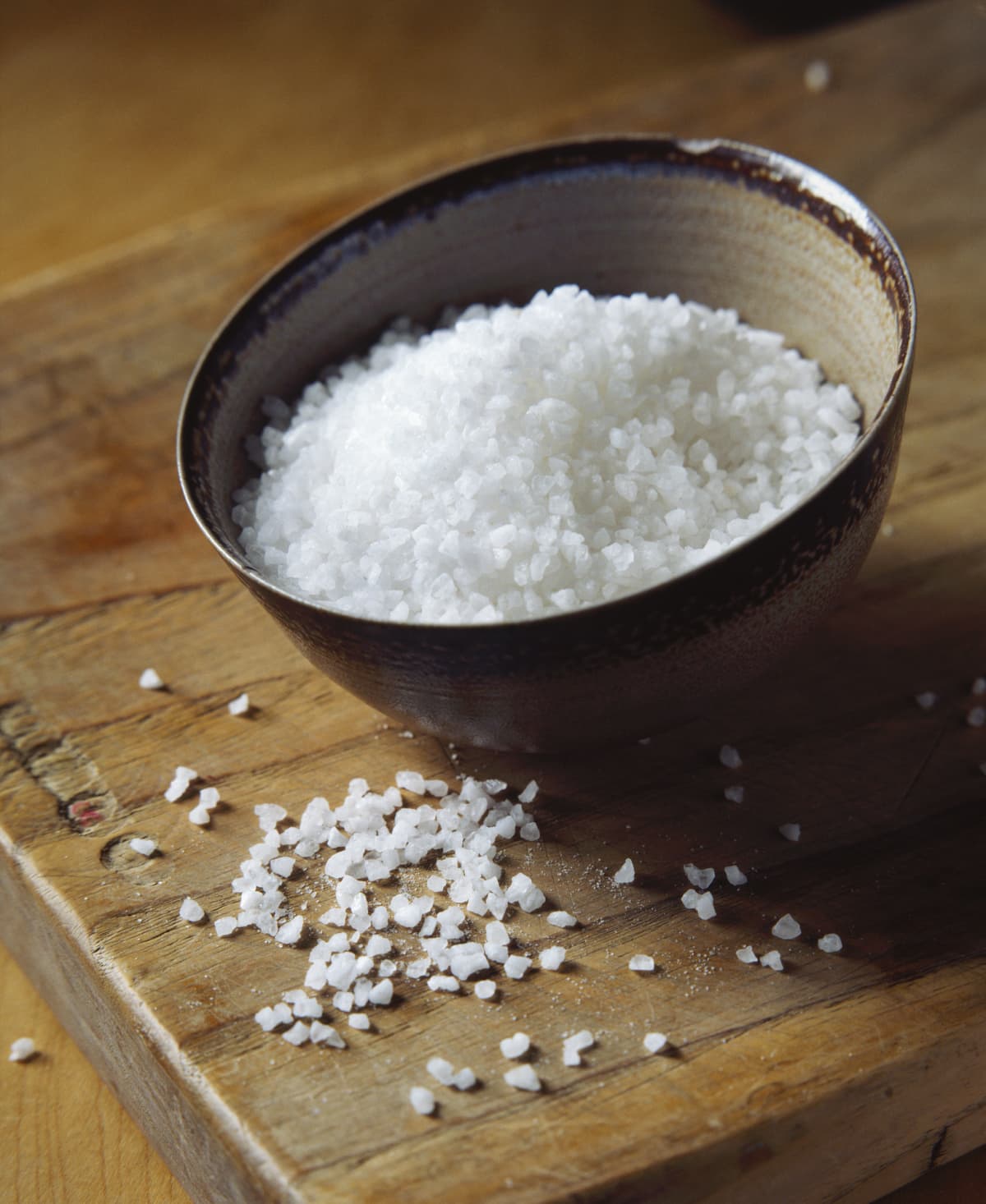 Natural sea salt in bowl on wooden cutting board