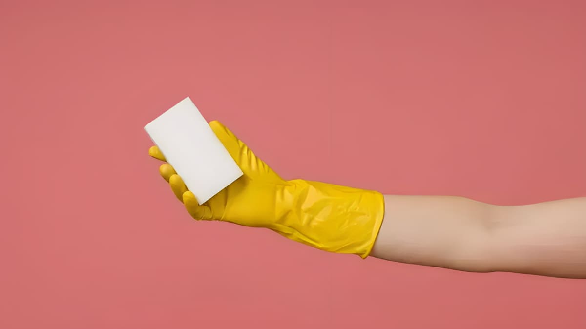 gloved hand holding a magic eraser sponge