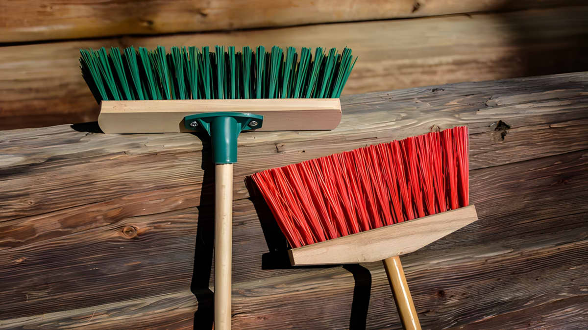A push broom and a regular broom on a wooden surface