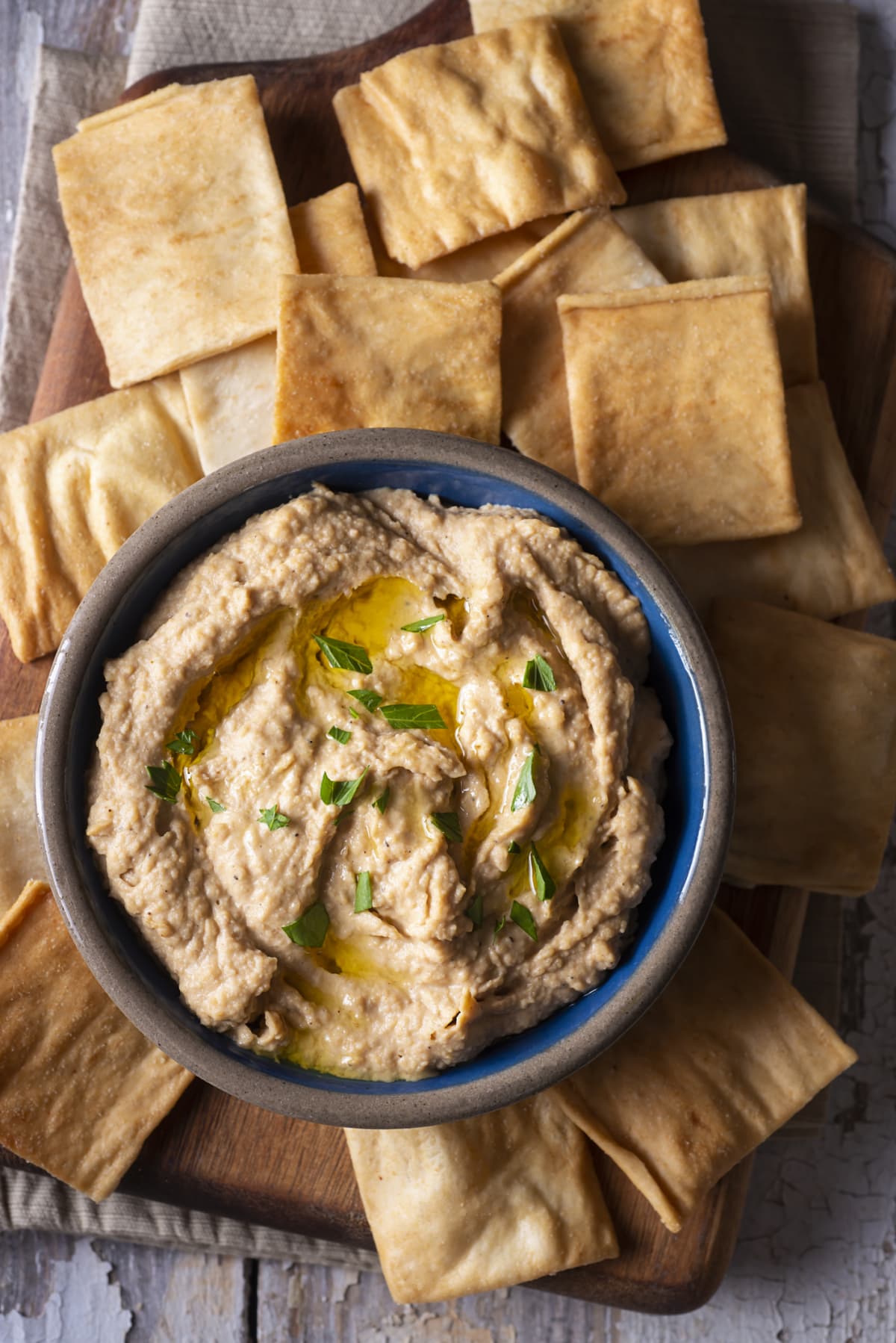 Hummus in a bowl, surrounded by pita chips.