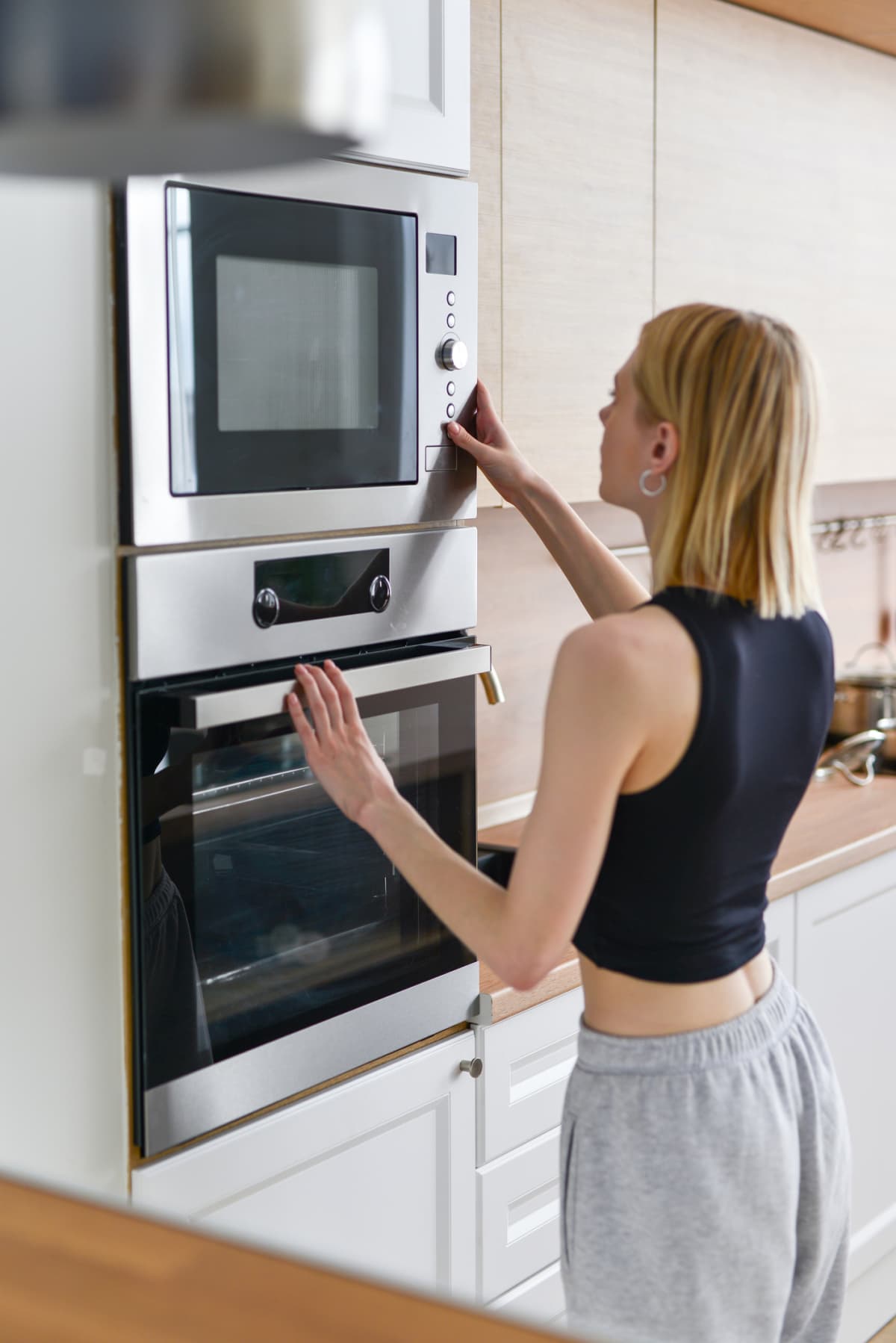 A woman places food in the microwave.