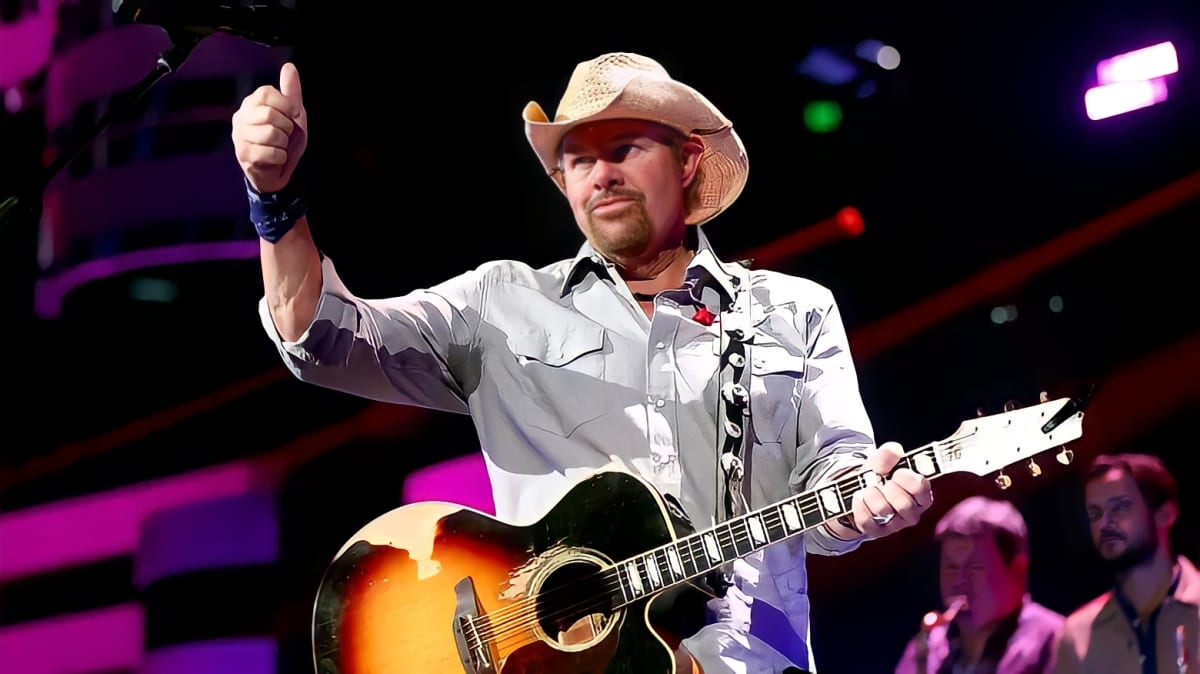 Toby Keith posing with a guitar.