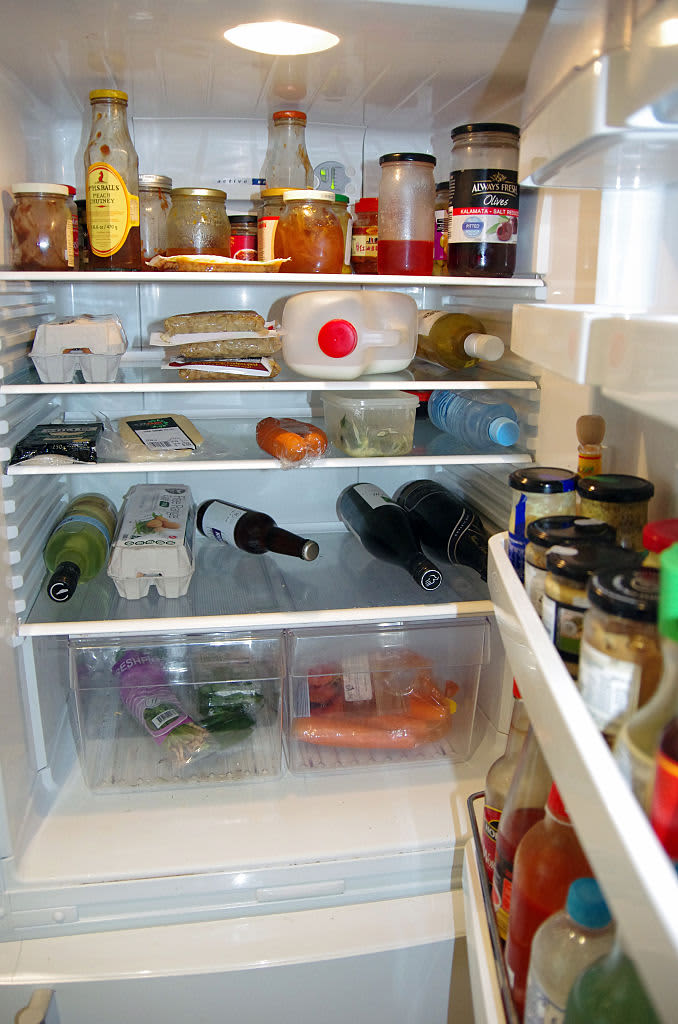 Open door of a home fridge with groceries stored inside