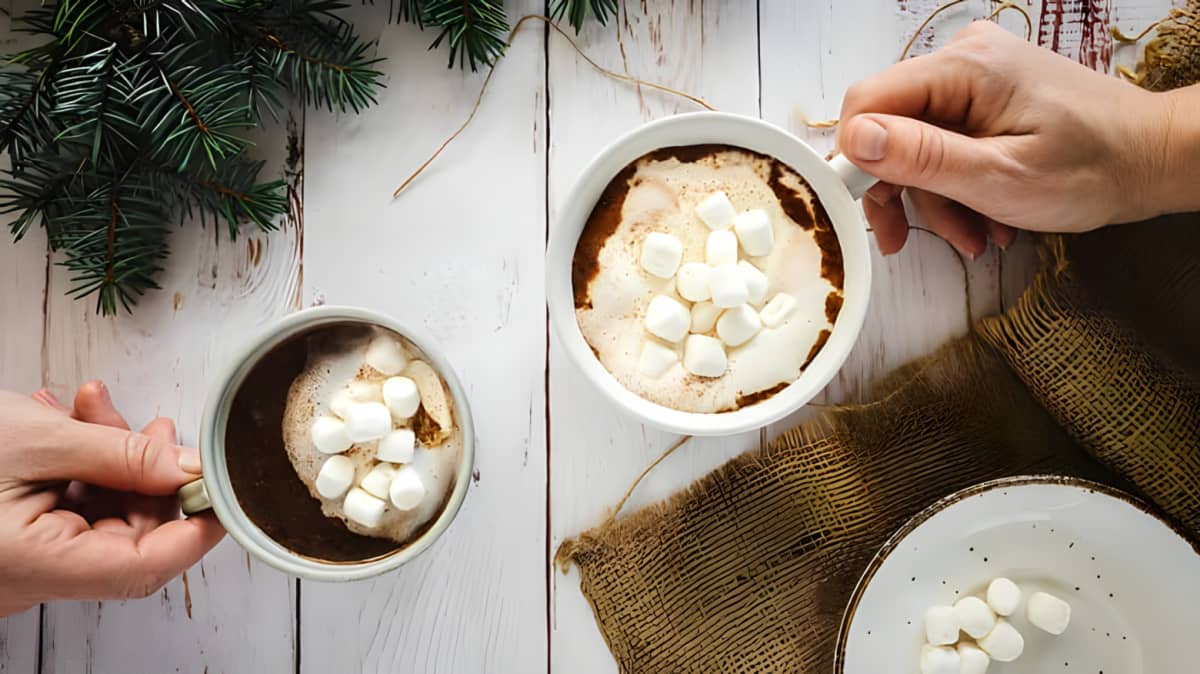 Two cups of hot chocolate with mini marshmallows on a white table background