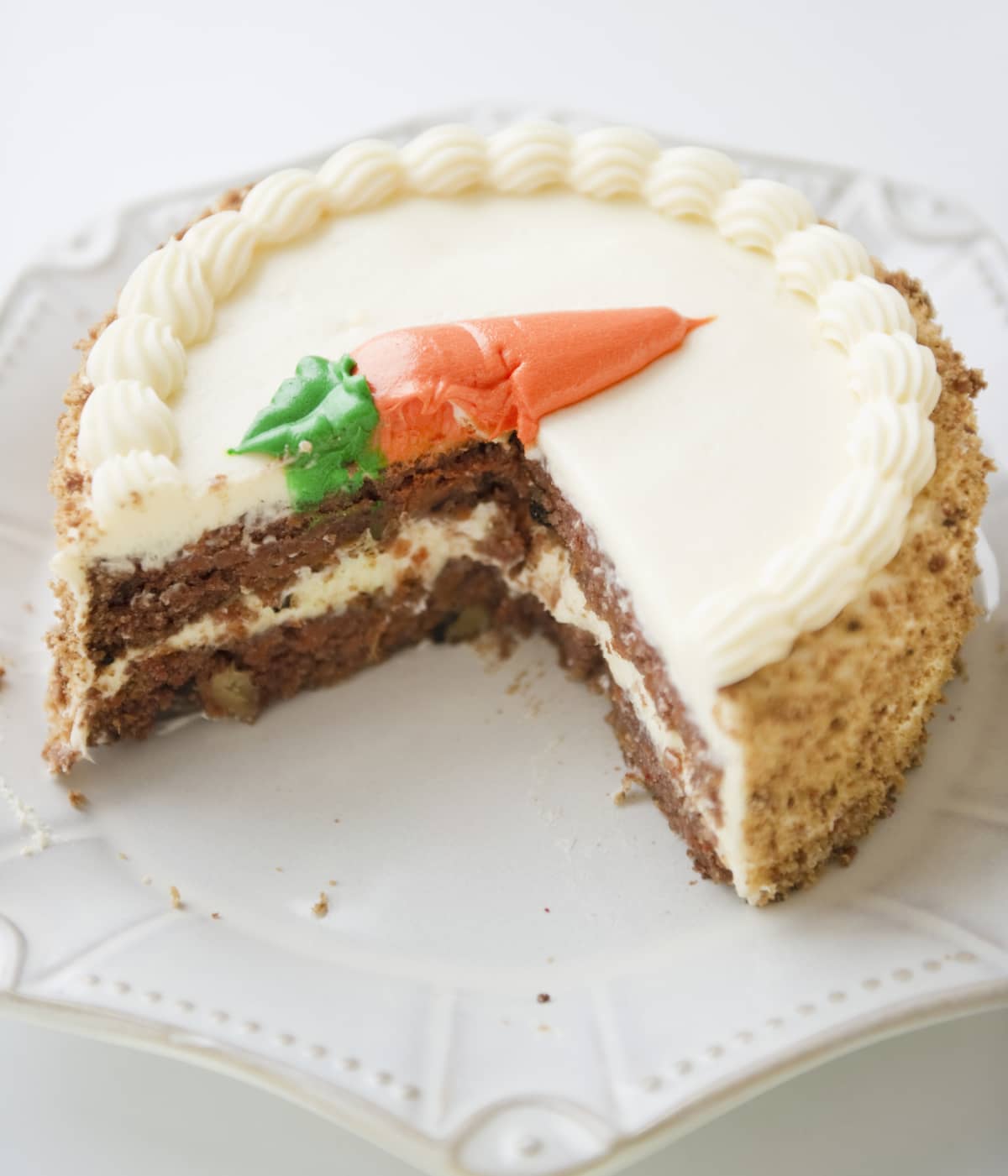 Carrot cake with some slices taken out on a white surface