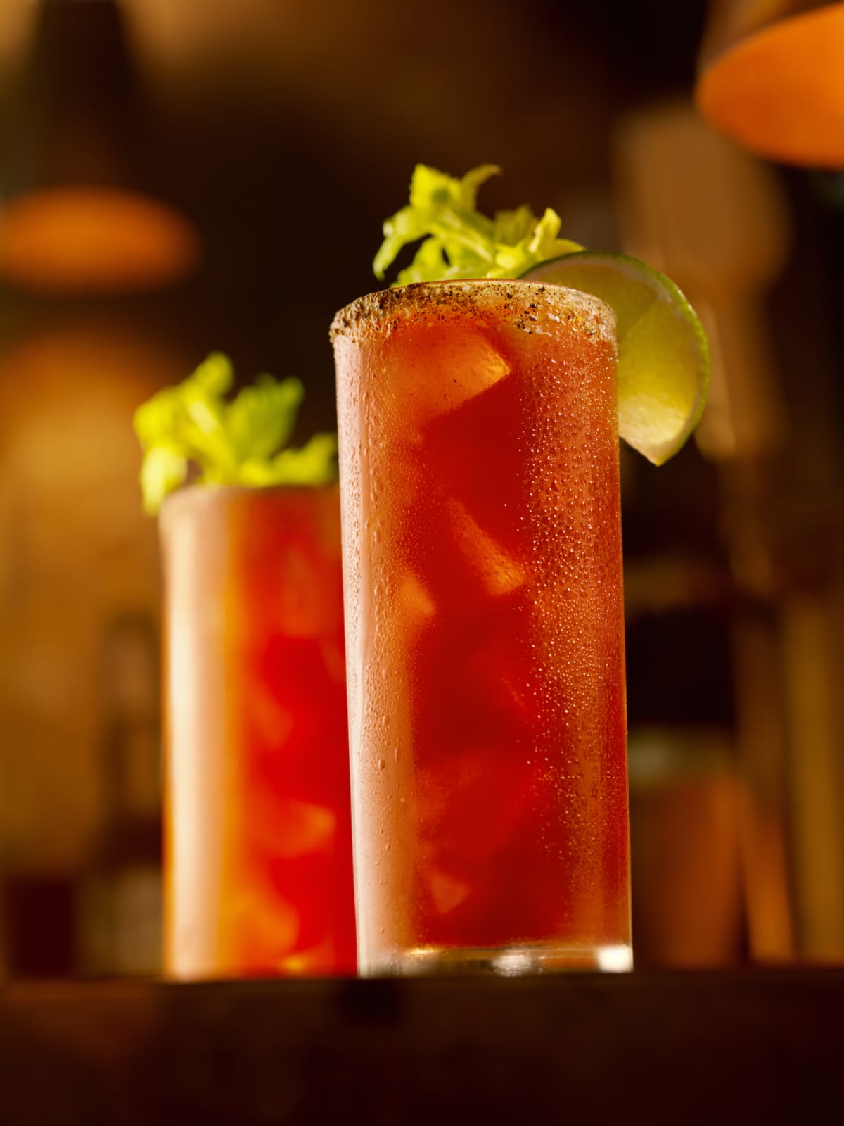 A bloody mary garnished with celery, bacon and olives.