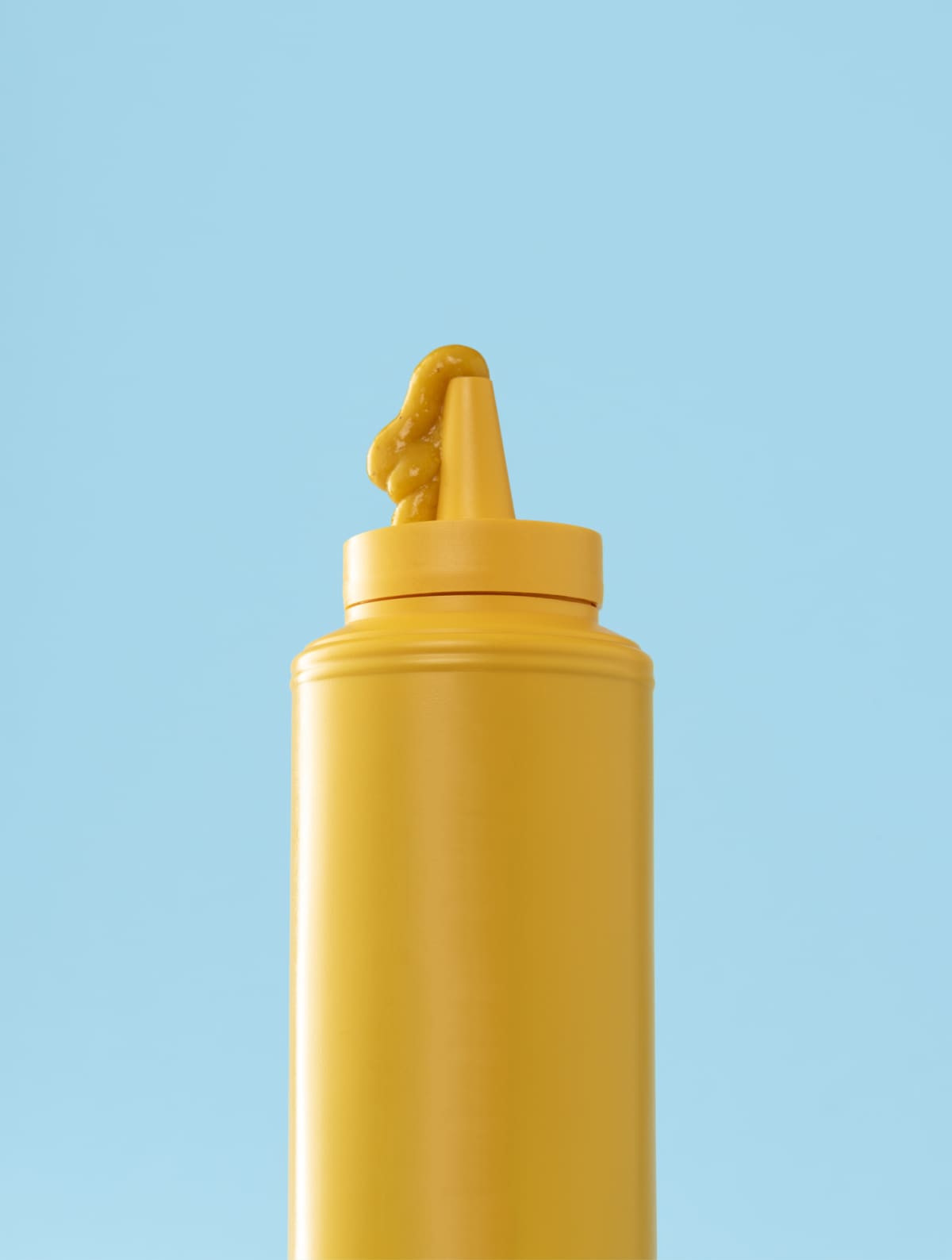 Mustard plastic bottle isolated on a blue background