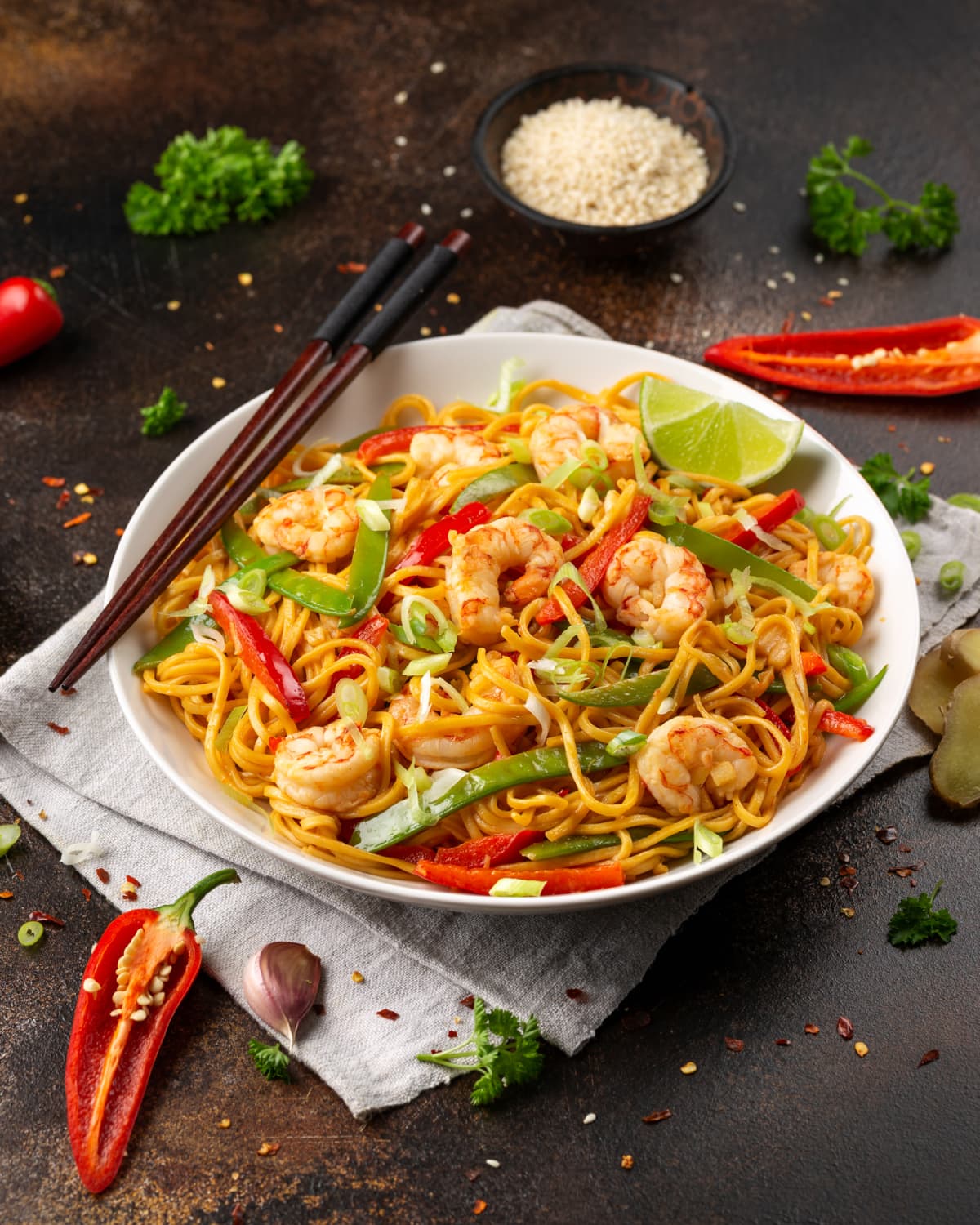 Stir fry noodles with prawns and vegetables on white plate with chopsticks