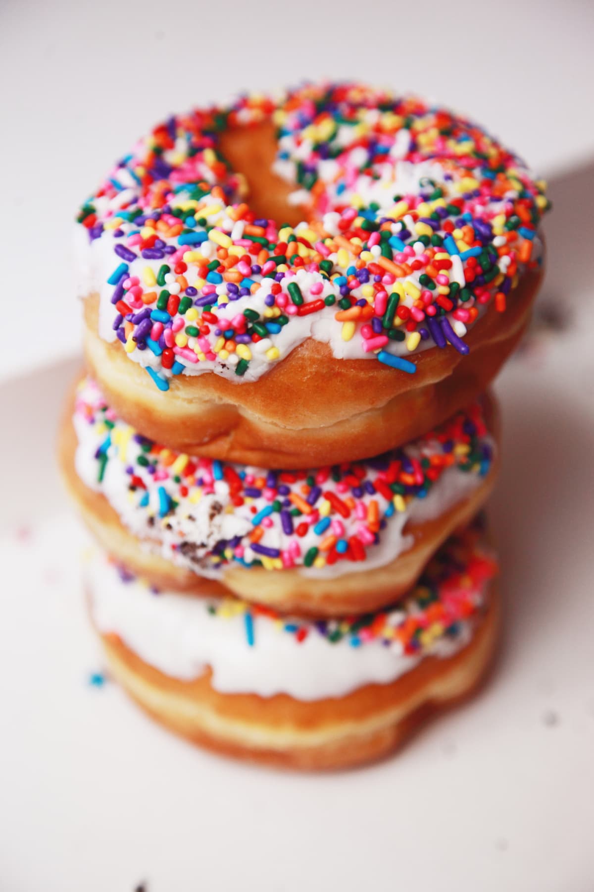 Stacked donuts with white frosting and rainbow sprinkles