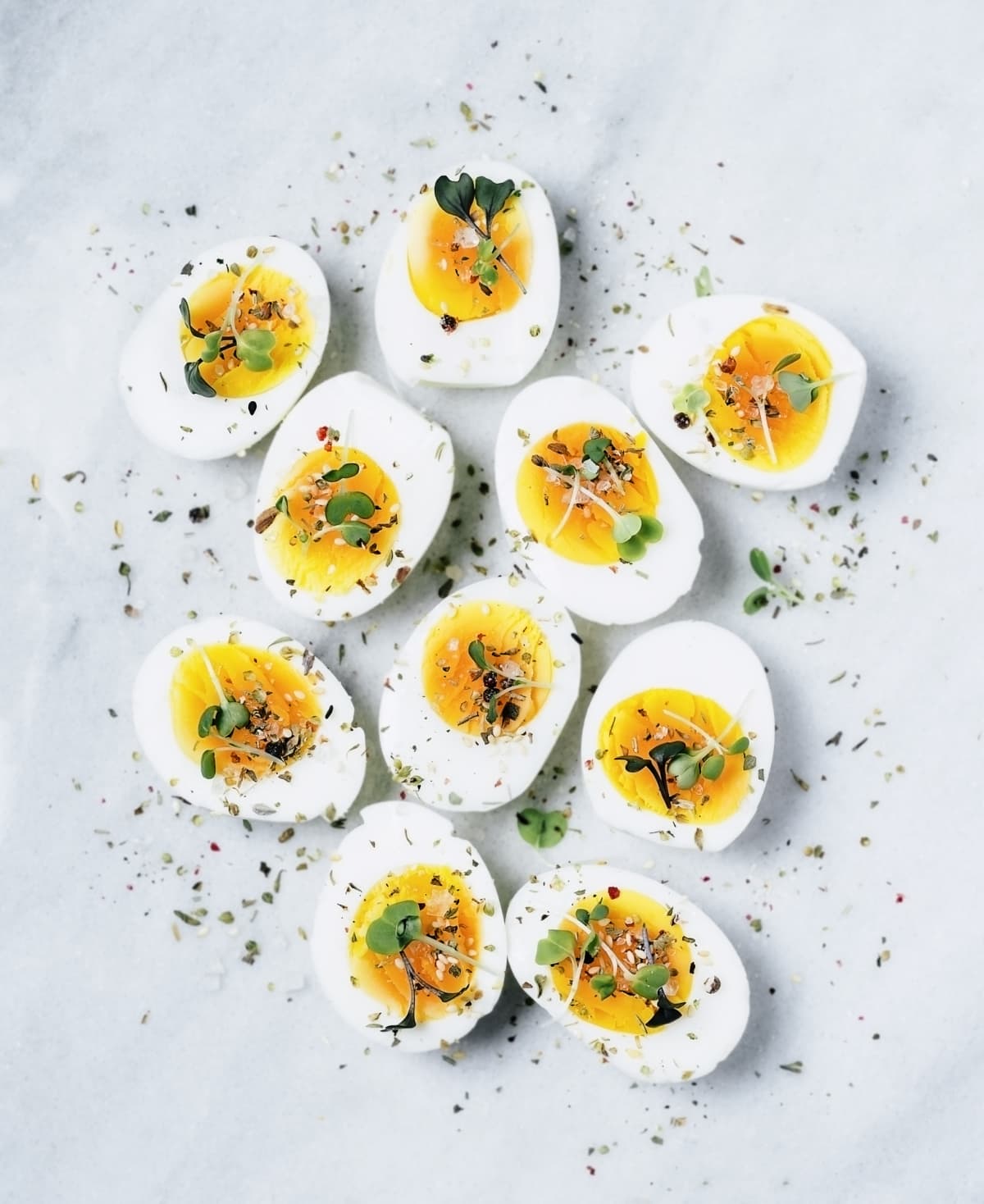 Several boiled eggs cut in half and topped with pepper and herbs