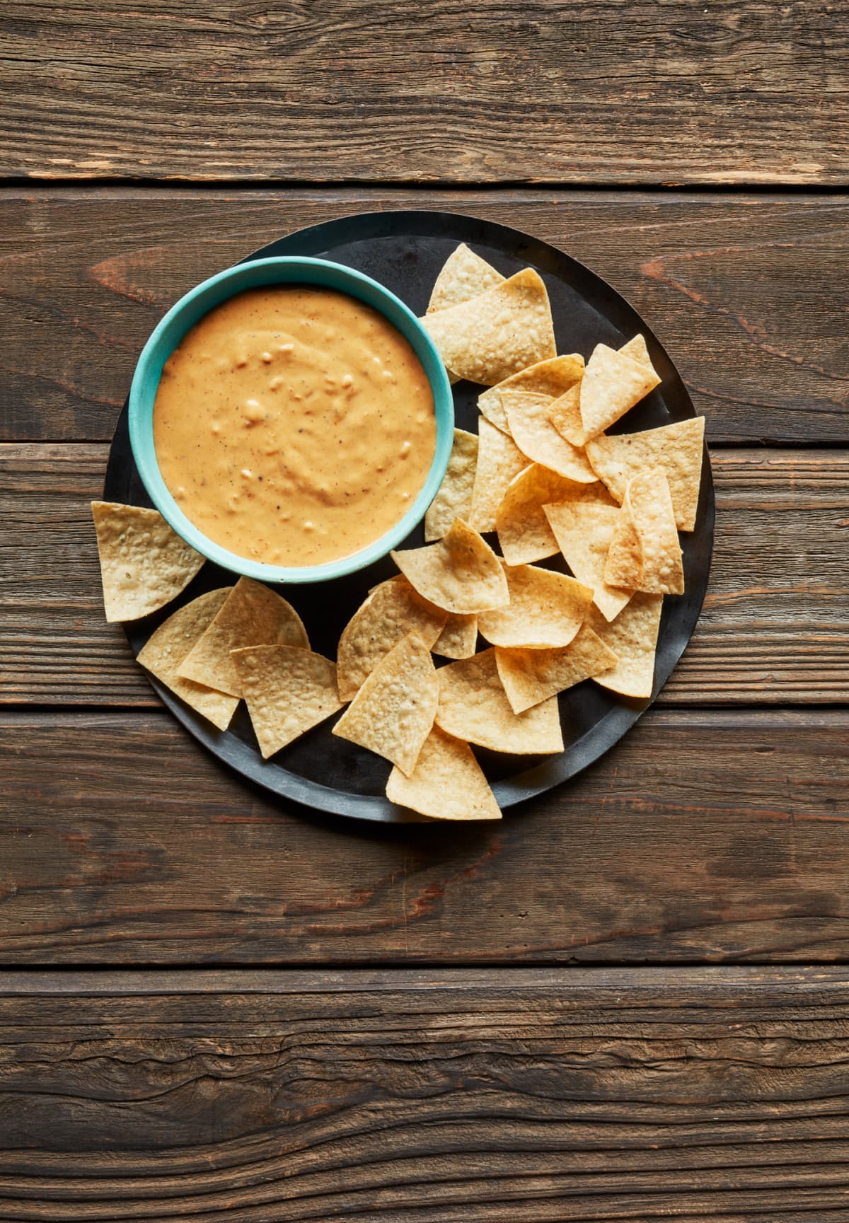 cheese dip in a blue bowl with chips on the side