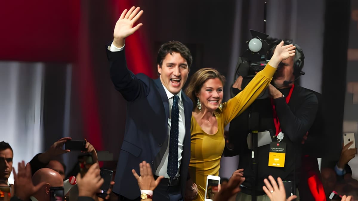 Justin and Sophie Trudeau smiling and waving at a crowd