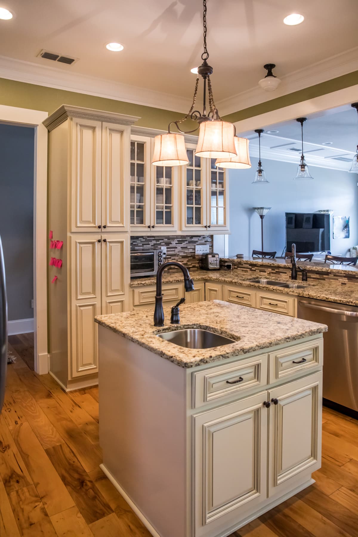 A square shaped kitchen with cream colored cabinets and granite countertops
