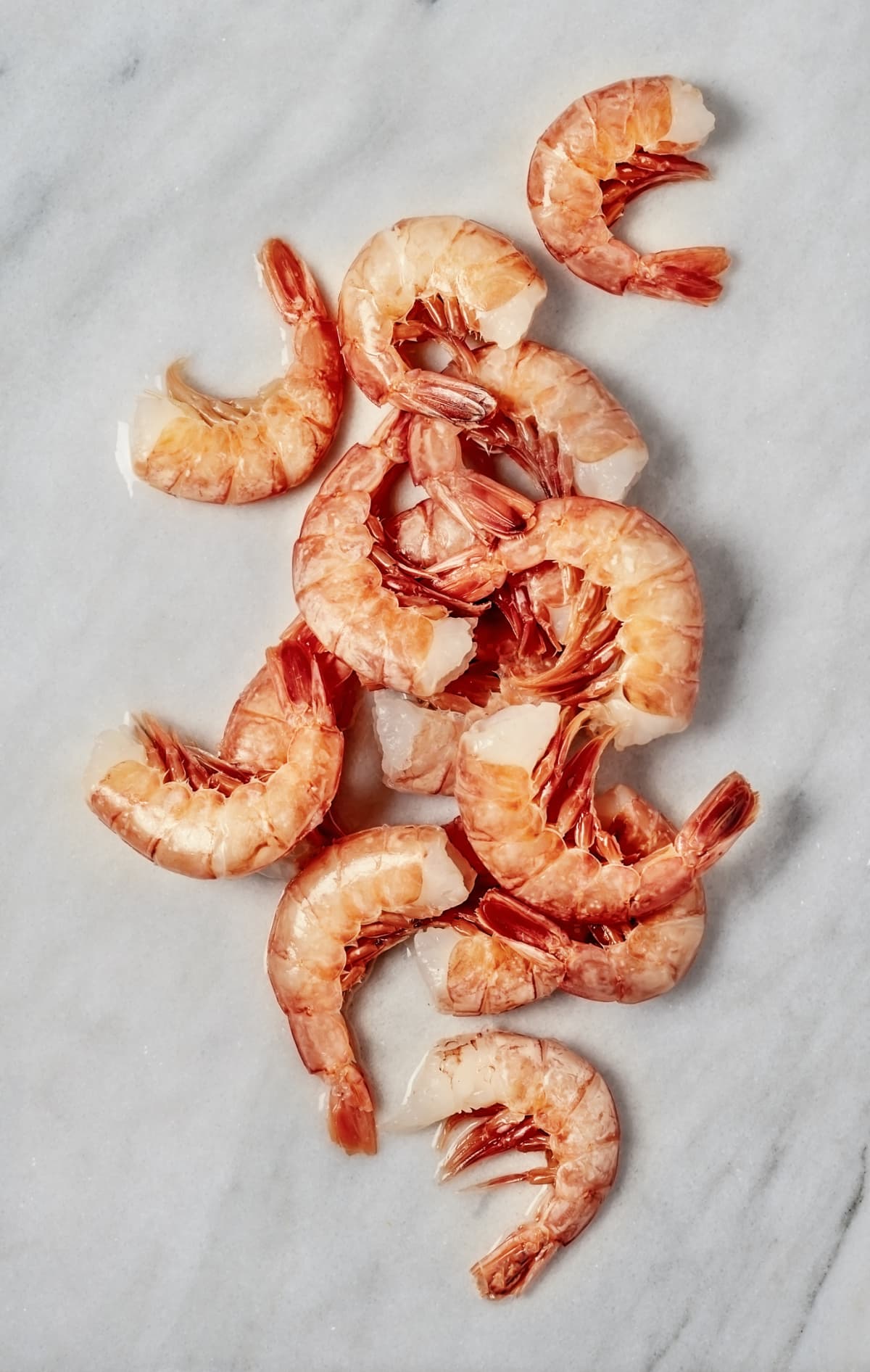 Raw shrimps with ice cubes on black background, copy space. Top view on appetizing seafood snack, restaurant serving backdrop.