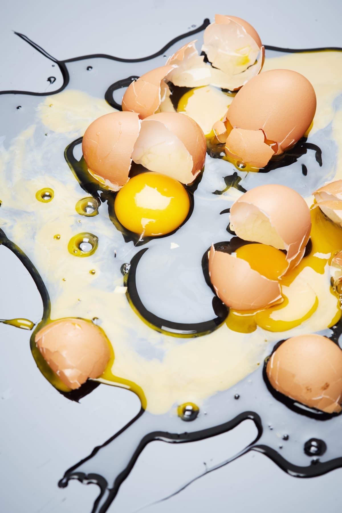 Many eggs lie broken on a shiny surface.