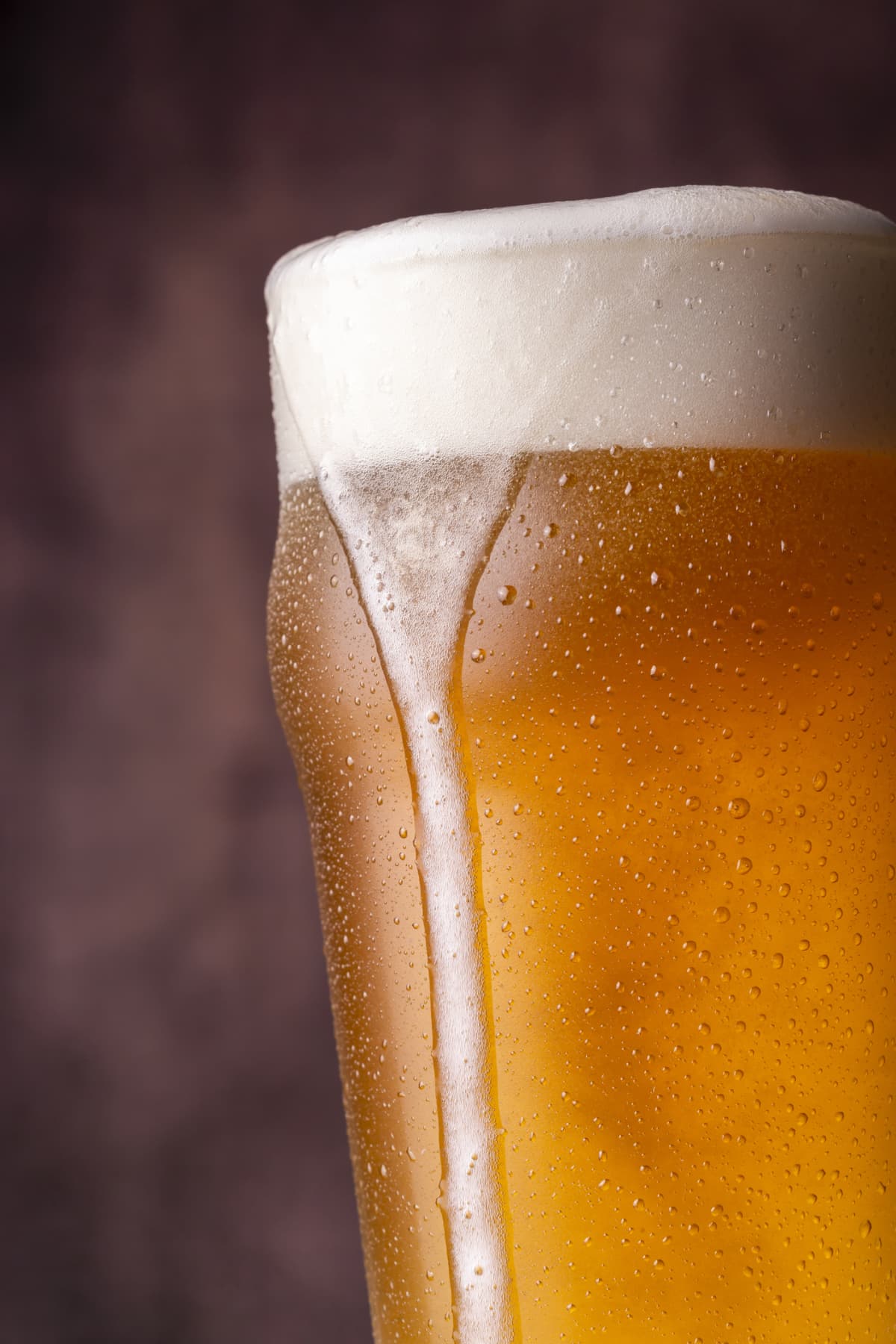 Detail of pint of cold pale beer with froth leaking over the glass