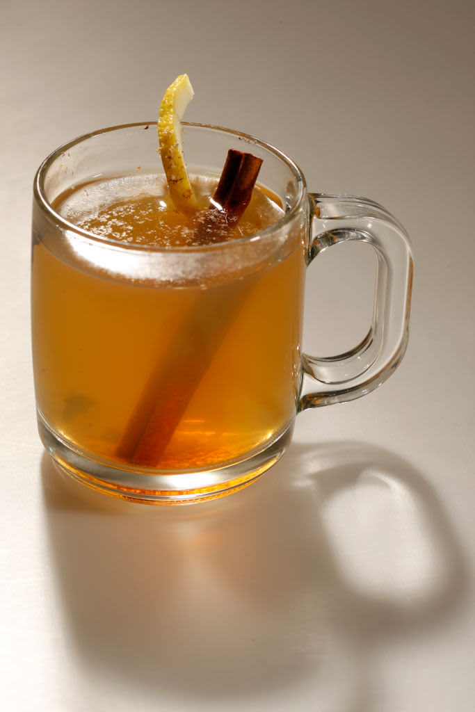 Toddy in glass mug with cinnamon and lemon peel