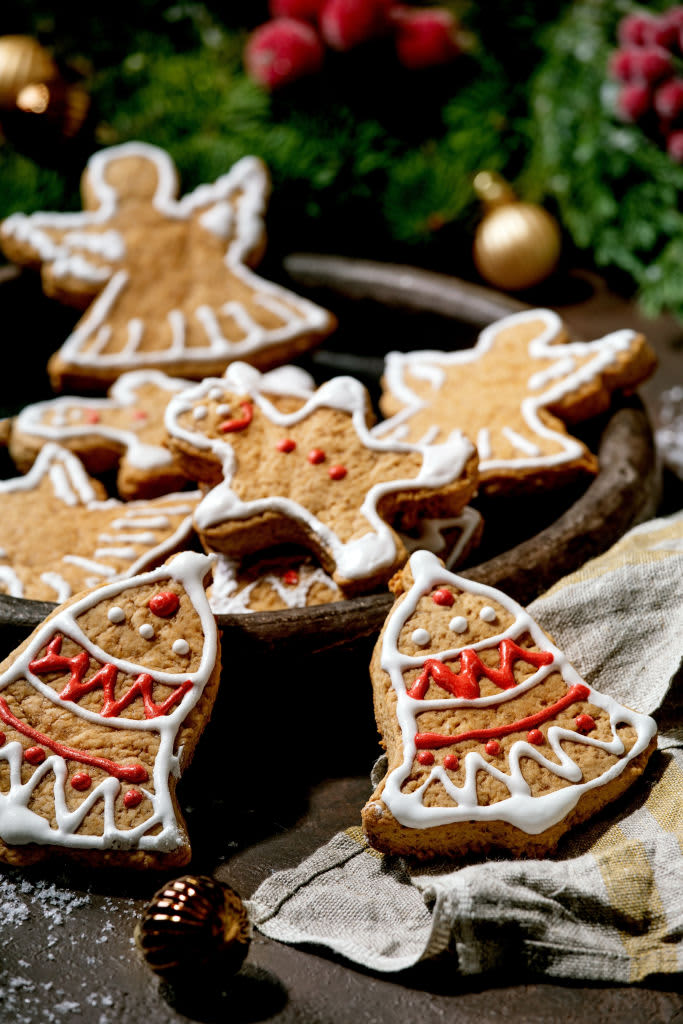 Homemade traditional Christmas gingerbread cookies with icing ornate. Gingerbread Man. angel. bell on ceramic plate with xmas decorations over dark background.. (Photo by: Natasha Breen/REDA&CO/Universal Images Group via Getty Images)