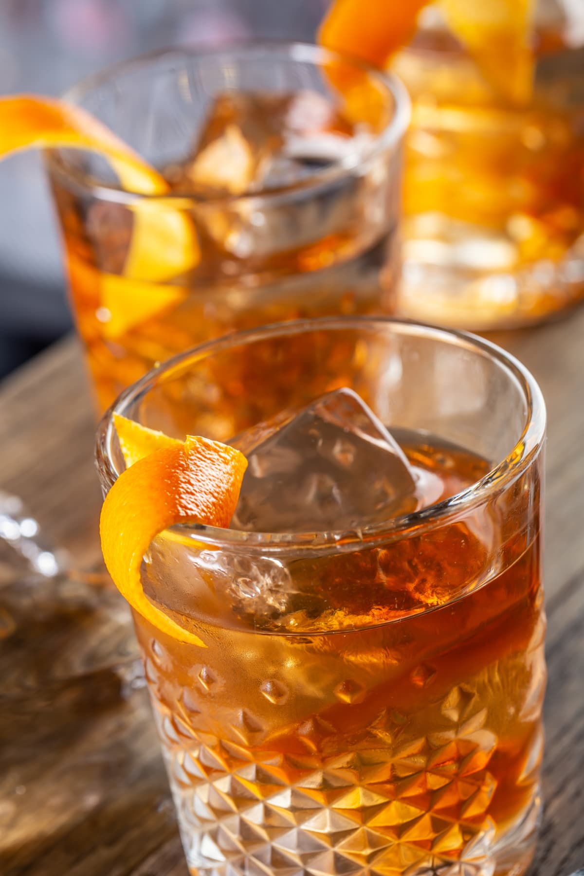 Old fashioned rum drink on ice with orange zest garnish.