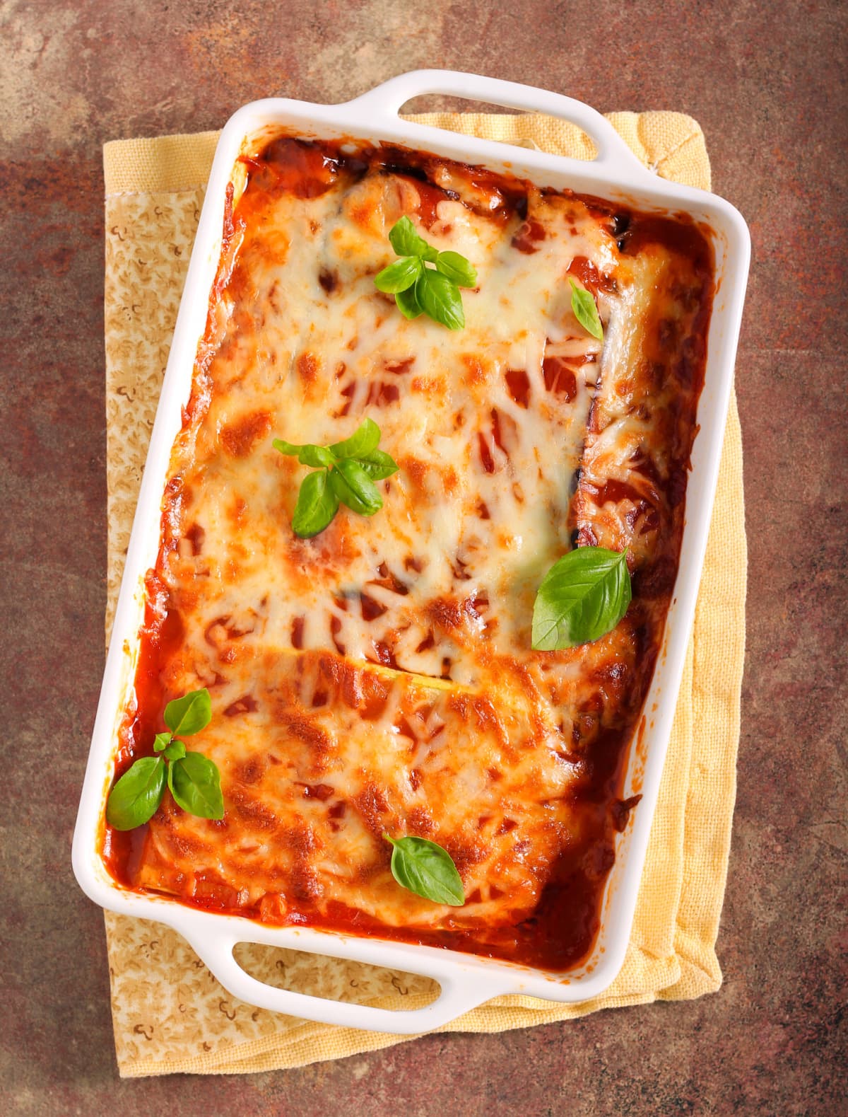 Bolognese Lasagna on a plate with yellow table surface and white background