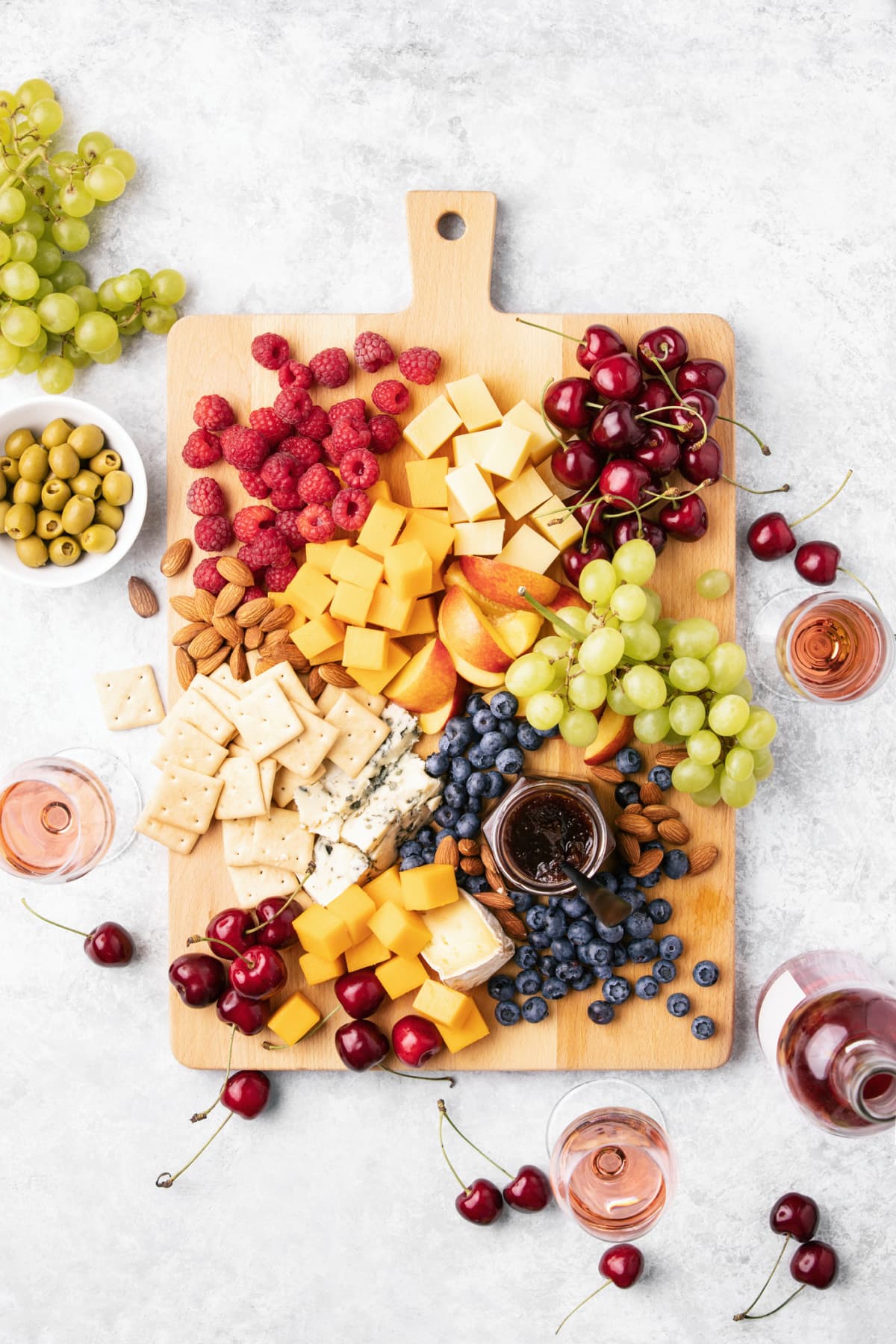 Summer cheese board with fresh ripe fruits and berries served with rose wine, view from above